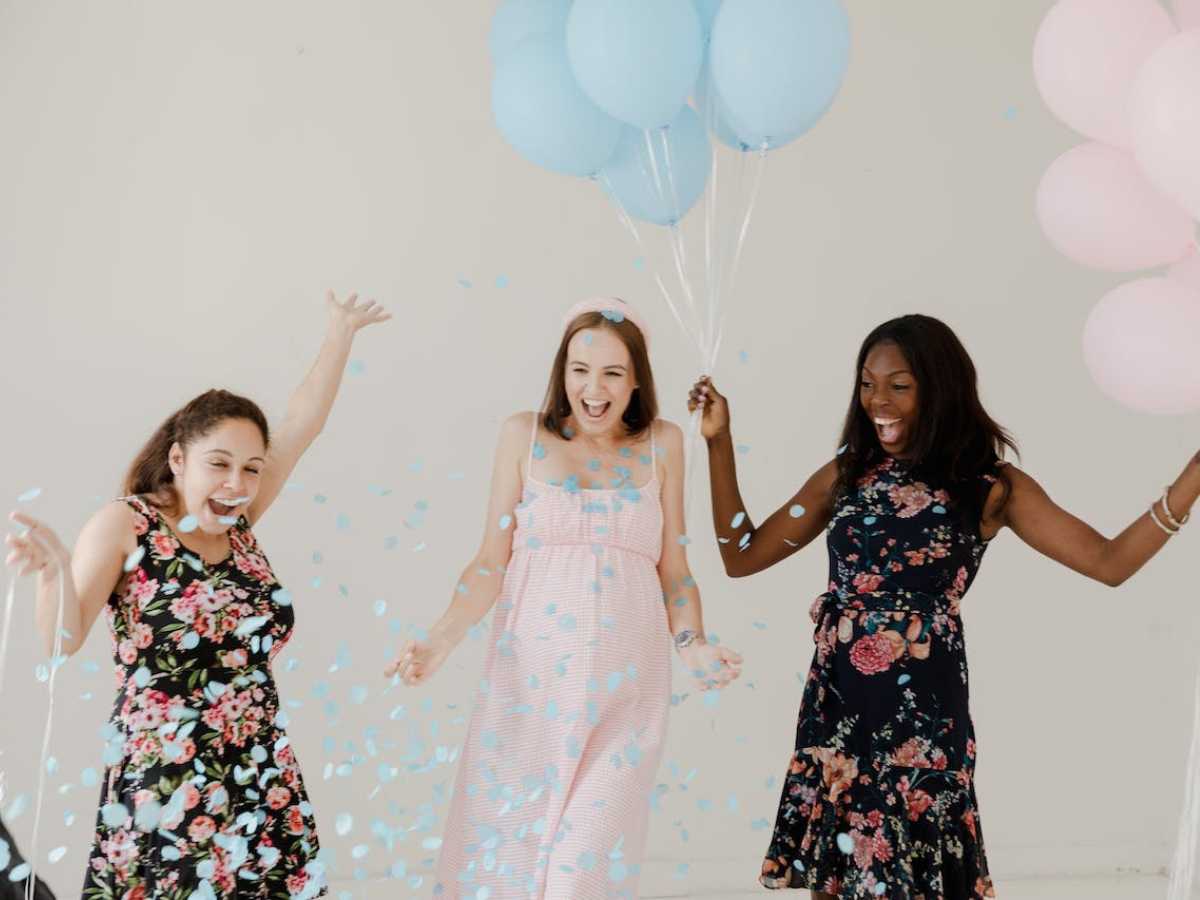 Three women with blue balloons and confetti