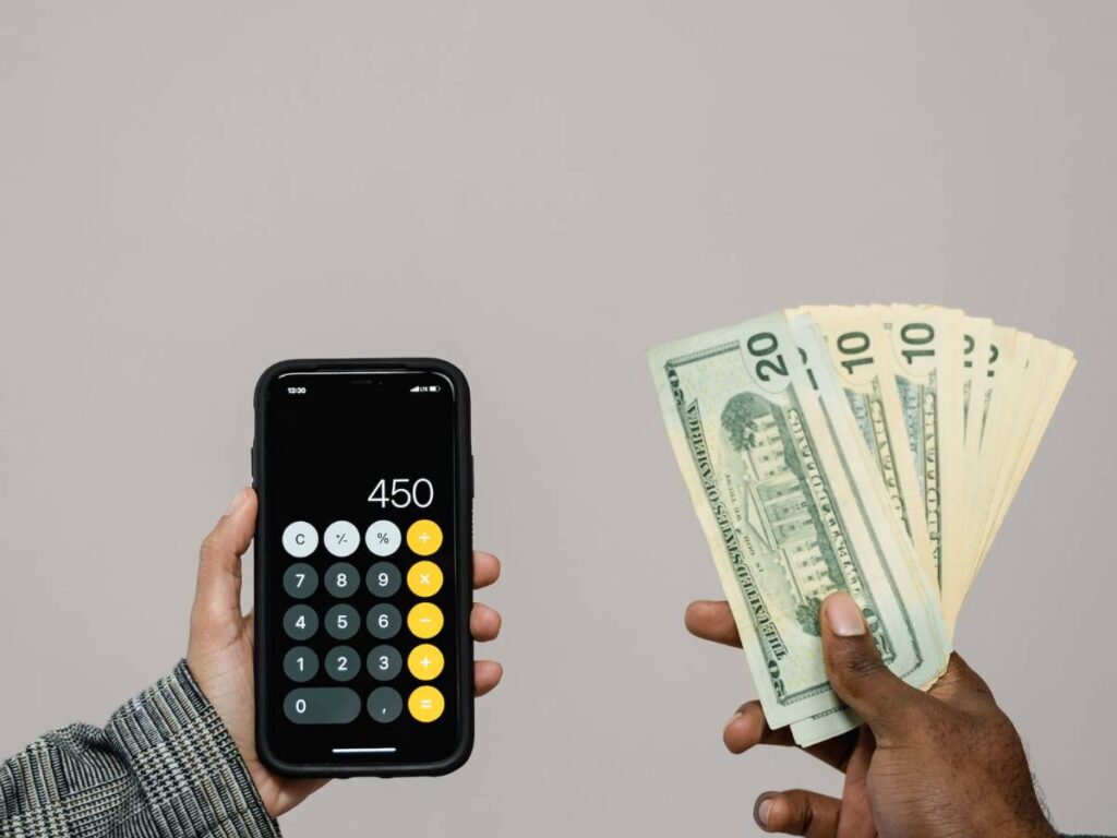 Hands Holding a Calculator and Cash Money