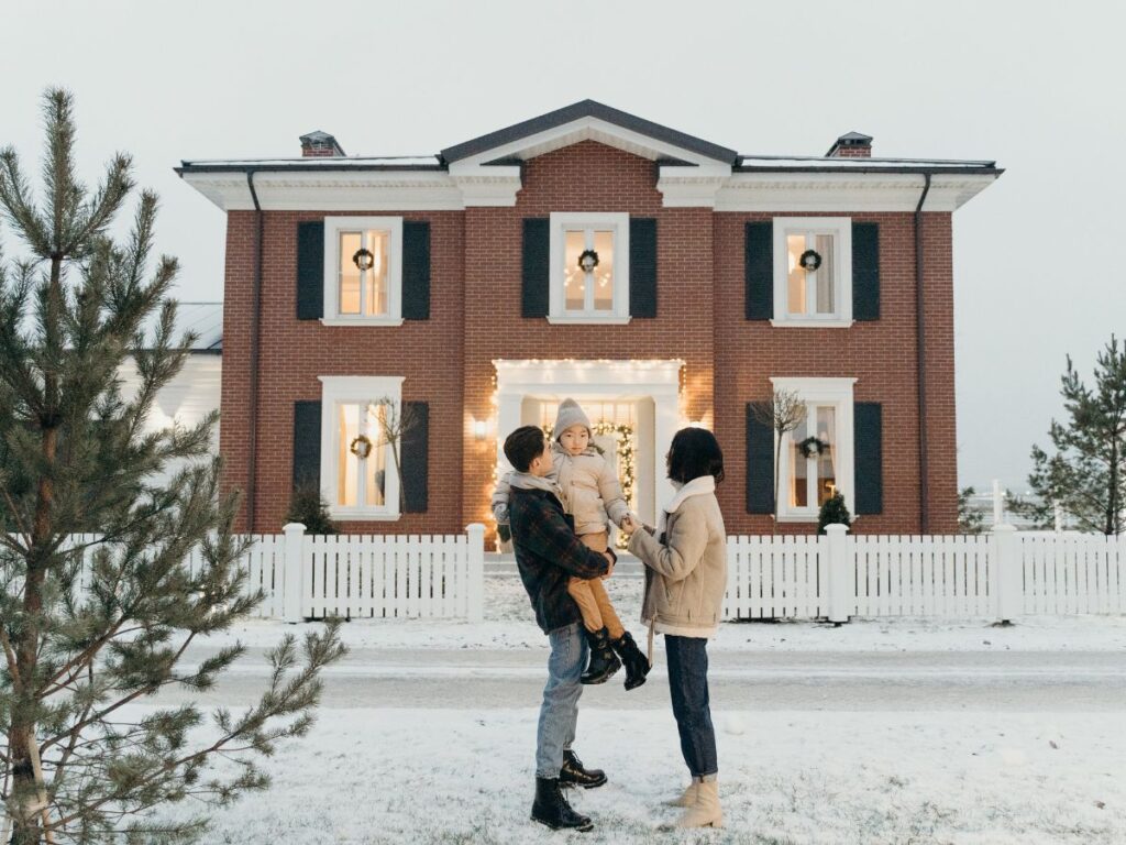Couple with a child in front of a house in winter