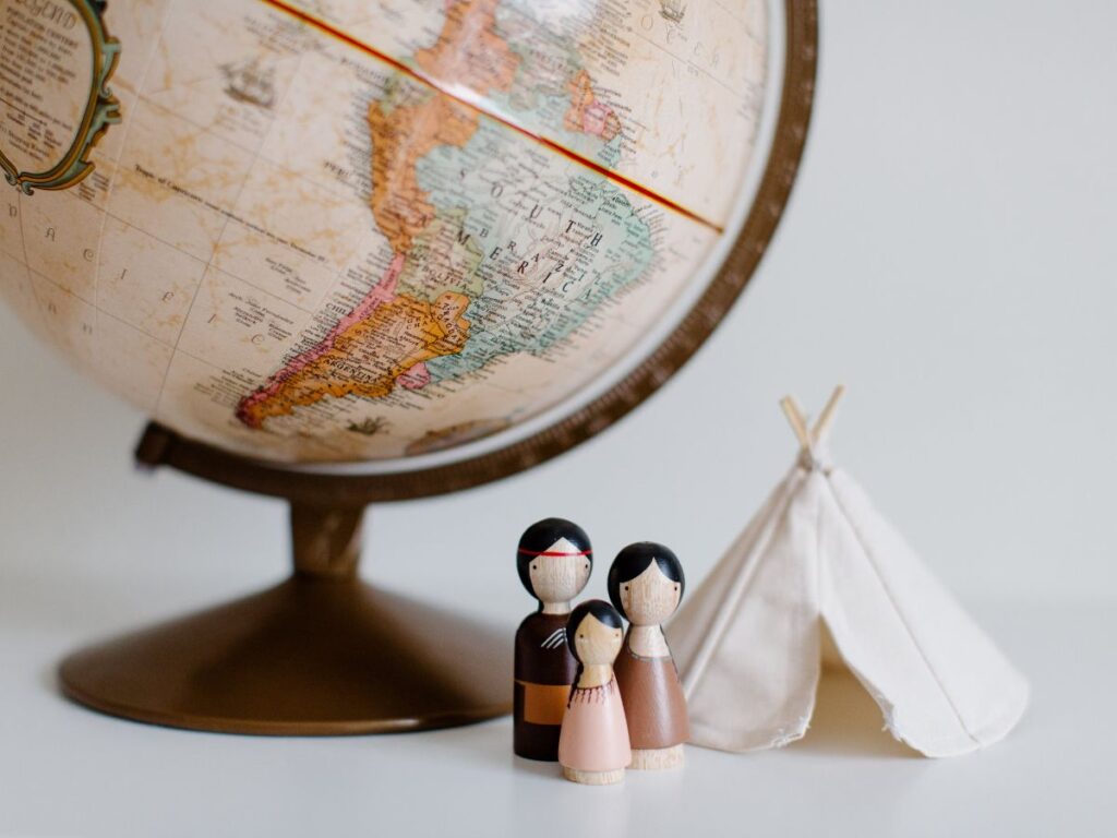 Retro globe with handmade toys against gray background in room