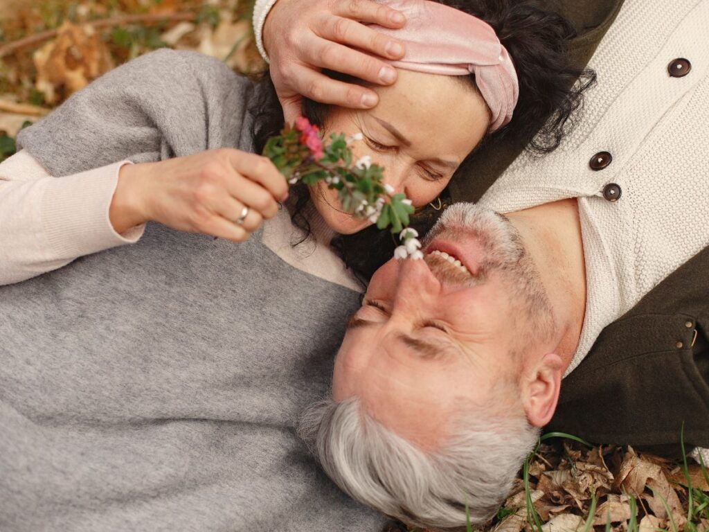 Happy senior couple in love with bunch of fresh flowers in nature
