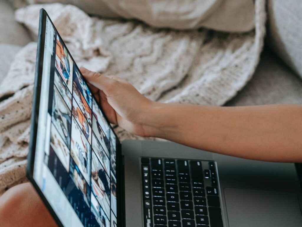 Faceless woman sitting on couch and working online on laptop