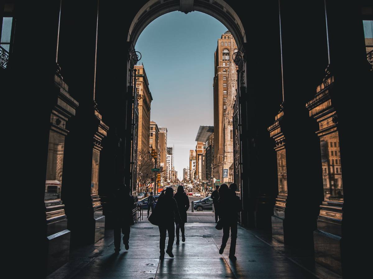 Silhouette Of People Walking On A Hallway Leading To The Streets