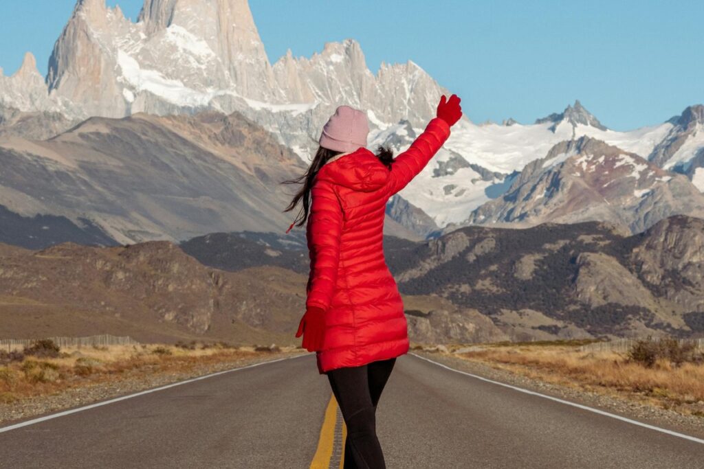Woman in Red Jacket Standing on Road with Mountains behind