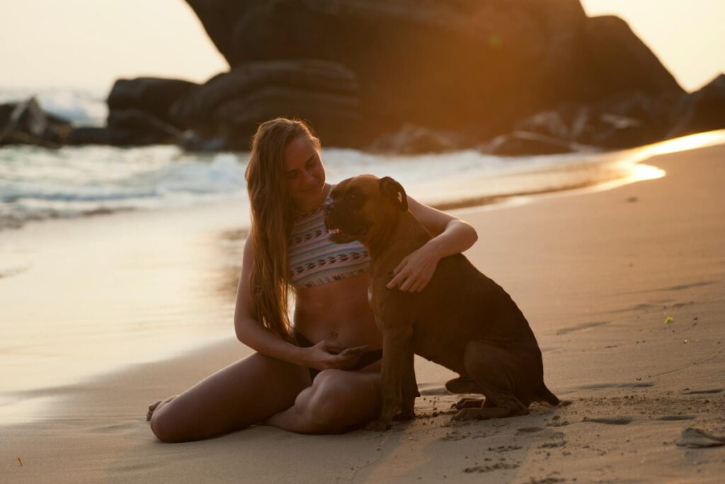 Woman Holding Boxer Dog on Beach Shore