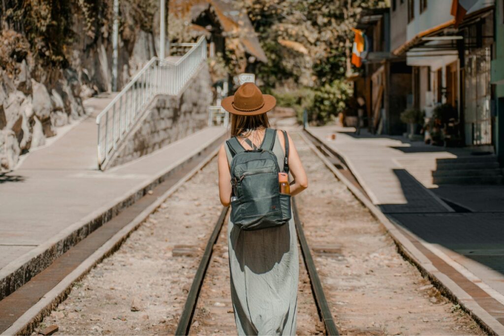 Back View of a Woman with a Backpack Walking on the Railway